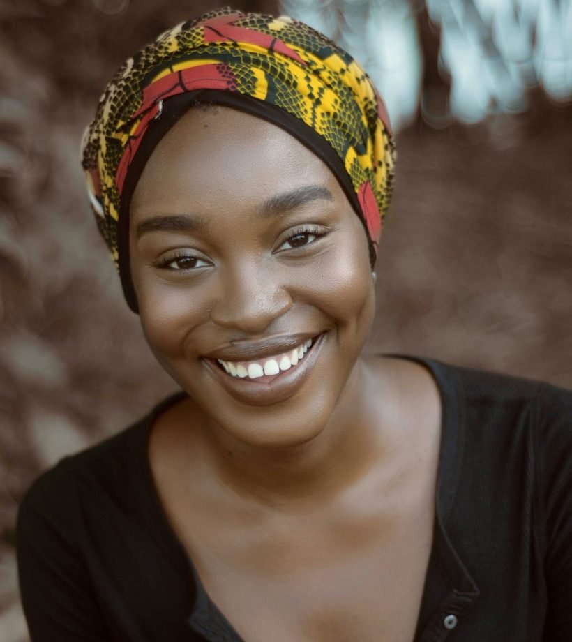 A smiling woman in a colorful headwrap radiating confidence