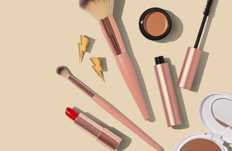 Beauty products and makeup brushes in soft pink tones